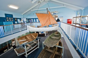Open wooden row-boats displayed in a large hall.