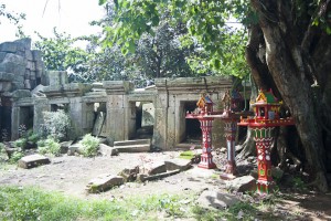 Red wooden Spirit Houses in front of the ruins of Wat Ek Phnom