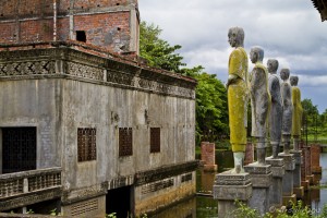 Standing yellow buddhist statues in a moat.