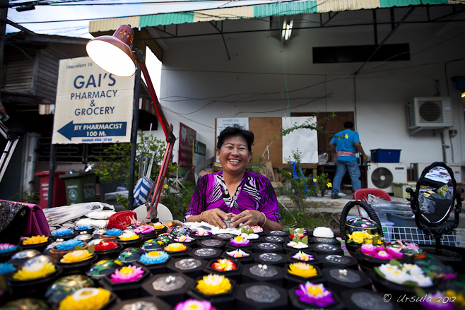 Smiling Thai woman sitting at a table of colourful carved soaps.