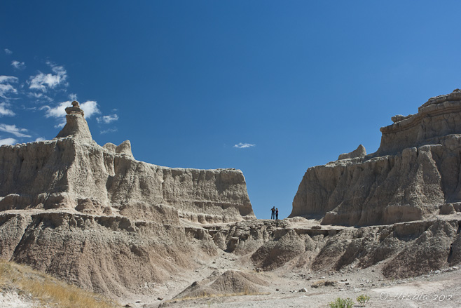 Two people are dwarfed by the rock formations of the SD badlands.