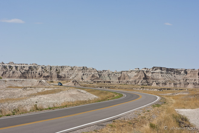 Curving road into dry badland mountains.