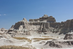 White rock formations, white sands and dry yellow grass, against a blue sky.