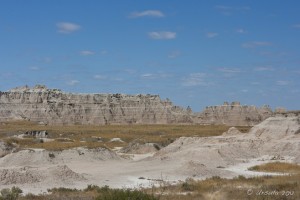 Badland rock formations behind dry grass.