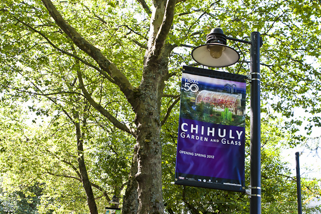 Purple poster for the Chihuly Garden and Glass Exhibition against trees.