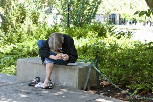 Man on a cement bench examining one foot.