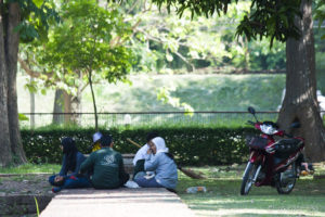Thai workers seated on grass in the shade.