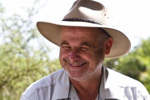 Portrait: elderly man smiling in a felt cowboy hat.