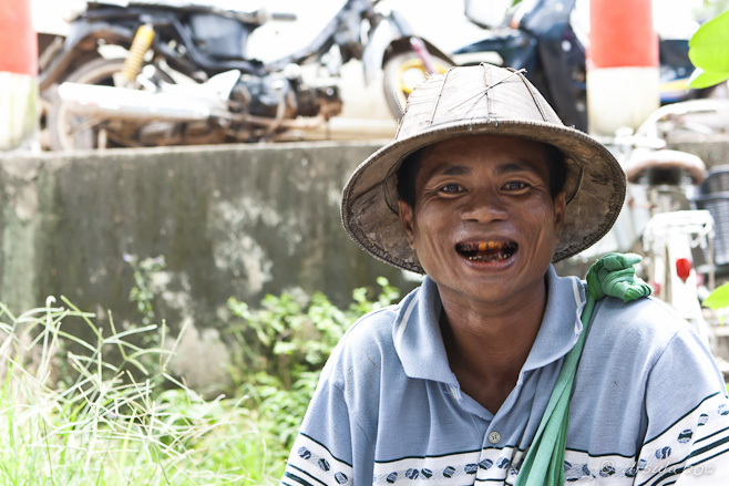 Portrait: Burmese man with beetle-juice teeth in woven bamboo hat 