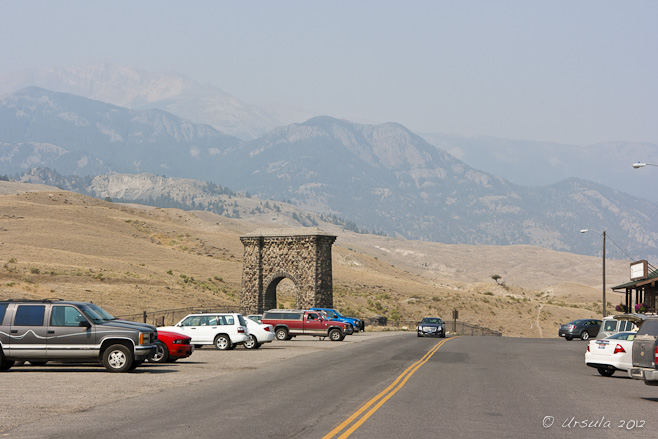 View: Roadway through Gardiner, the Roosevelt Arch and mountains.