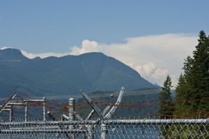 Fencing with barbed wire; mountains behind. Stave Falls Powerhouse