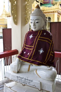 Marble seated buddha, draped in a purple cloth.