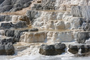 White, yellow, black and brown limestone terraces with yellow water pooling. Minerva Terrace