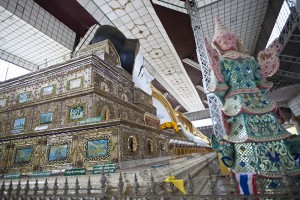 Back view of piled jewelled chests with Buddha head resting; jewelled deva watching over.