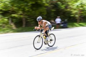 Panning shot: Smiling male cyclist on a tropical highway. Koh Samui Triathlon 2012.