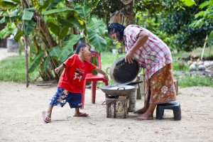A thai boy helping mum cook on an outdoor burner. Koh Samui