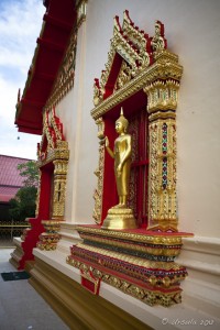 Thai temple window with a golden standing buddha.