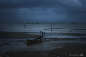 Dark night scene: Small wooden boat beached on a low tide, Koh Samui