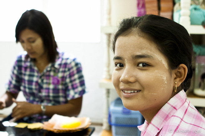 Portrait: Young Burmese woman with thanakha on her face, in a gold leaf workshop.