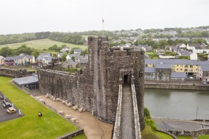 A view of a wet Pembroke Castle tower, the houses of the city in the background.
