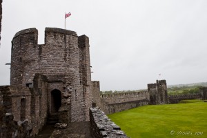 A Union Jack flies against a wet grey sky over a Pembroke Castle Tower