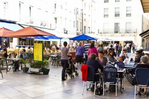 Outdoor scene: people eating at coffee shop tables in a plaza. Nîmes