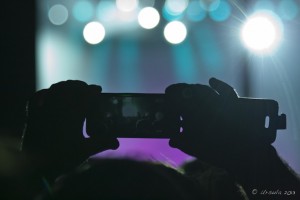 Silhouetted hands holding a smartphone at a concert