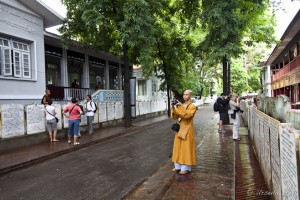 Chinese Monk in long yellow robes in the wet street through Mahagandayon Monastery