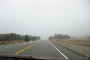 Landscape: Highway through a car windscreen, disappearing into wet cloud.