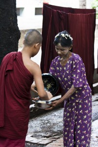 Young monk giving food to an indigent woman, Mahagandaryon Monastery