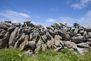 Rough-hewn stones piled into a wall against blue sky, the Burren, Co Clare, Ireland.