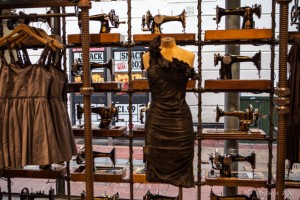 A window in a women's clothing store, lined with old black singer sewing machines, looking out over a wet Brighton street.