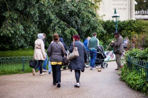 People in jackets and raincoats in the grounds of the Royal Pavilion, Brighton, as a clarinetist plays. Brighton, UK.