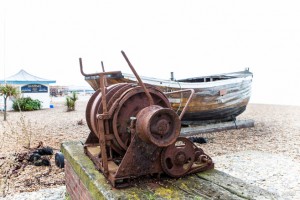 A rusty winch and an old wooden boat sit on Brighton Beach, UK