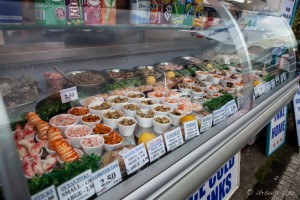 A glass case of small styrofoam cups of seafood, Brighton Beach, UK