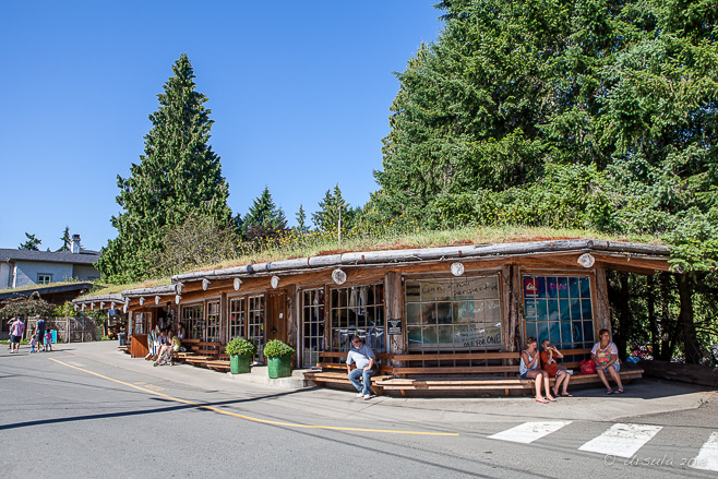 People sit outside the wooden buildings of the Coombs Country Market, BC