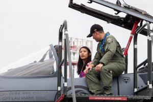 An Asian woman inside a fighter airplane, Singapura Airforce personelle outside, Singapore Airshow 2014