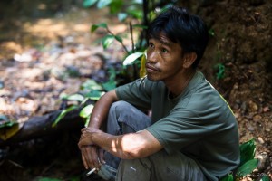An official Gunung Leuser National Park Guide, sitting and smoking.