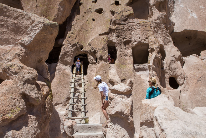 People climbing a wooden ladder into a Cliff Dwelling, Badelier National Monument