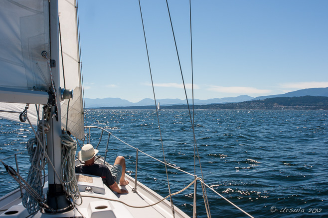 Man resting on the prow of a sailboat, Strait of Georgia