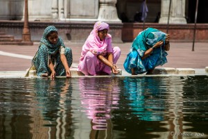 Three women in Saris squatting around the Reflecting Pond, Jama Masjid, Old Delhi