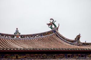 Traditional Chinese dragon and red, round roof tiles against a white sky, Longshan Temple, Quanzhou China