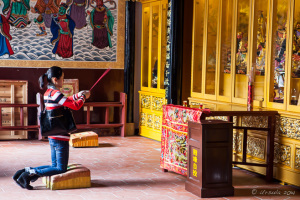 Young woman kneeling with joss sticks, Longshan Temple, Quanzhou China