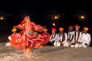 A Kalbelia Dancer in a red gypsy dress and musicians, Manvar Desert Camp, Dechu, India