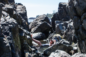 Woman lying in a rock pool, Hot Springs Cove, Maquinna Marine Provincial Park BC