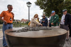 A woman points out landmarks on a metal Regensburg City-Map Diorama, Bavaria