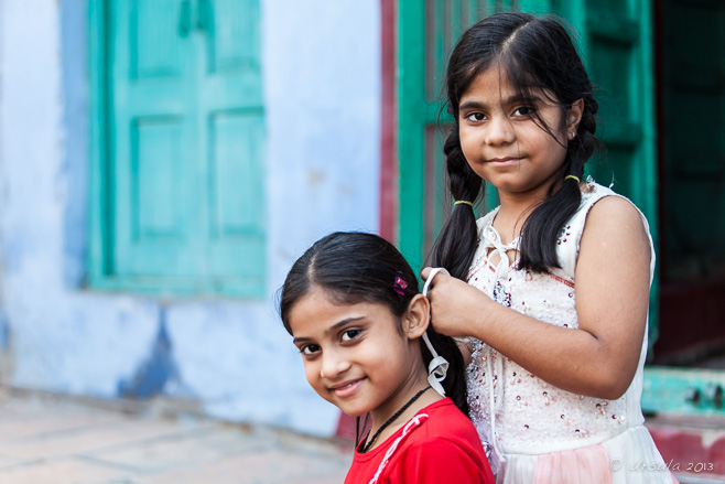 Young Indian girls smile as one fixes the others hair,  Jodhpur Rajasthan India