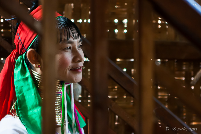 Kayan Lahwi (Padaung Long Neck) Woman through teak bannisters,  Inle Lake Myanmar