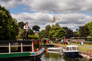 A man throwing a line to shore from atop a canal boat, Tiverton Canal Company, Devon UK