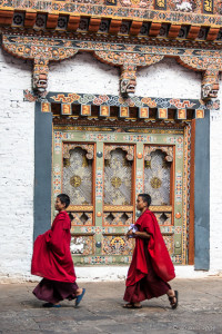 Monks Walking in front of a decorated doorway, Punakha Dzong, Bhutan